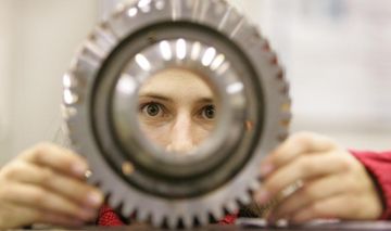 Studentin der Fachrichtung Maschinenbau an der RWTH schaut durch das Loch eines Werkstücks