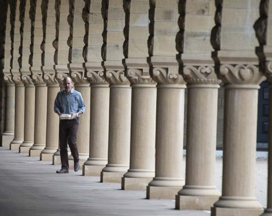 Ein Mann läuft auf einem Säulengang auf dem Campus der Stanford University.
