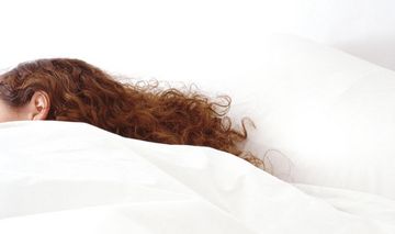 Kopf einer schlafenden Frau unter einer Bettdecke
