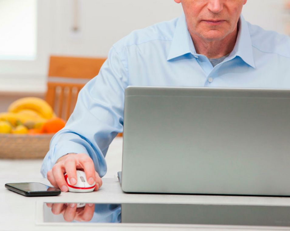 Mann arbeitet am laptop im Homeoffice, im Hintergrund steht ein Obstkorb.