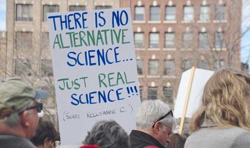 Demonstrierende mit Protestplakaten für "real science"