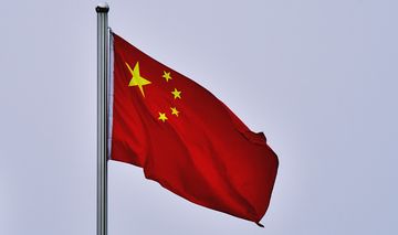 Die chinesische Flagge vor grauem Himmel.