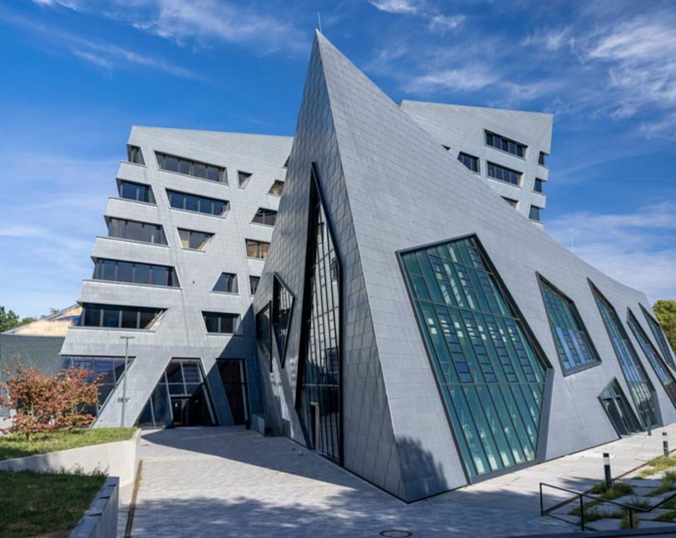 Ein futuristisch anmutendes Gebäude mit vielen Glasfronten und Pyramidenformen. 