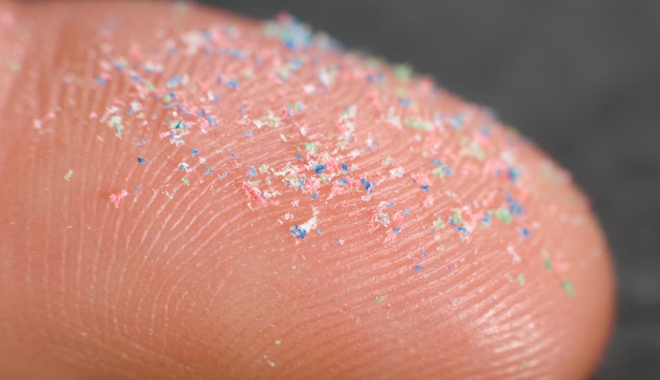 bunte Mikroplastik-Partikel auf einer Fingerkuppe