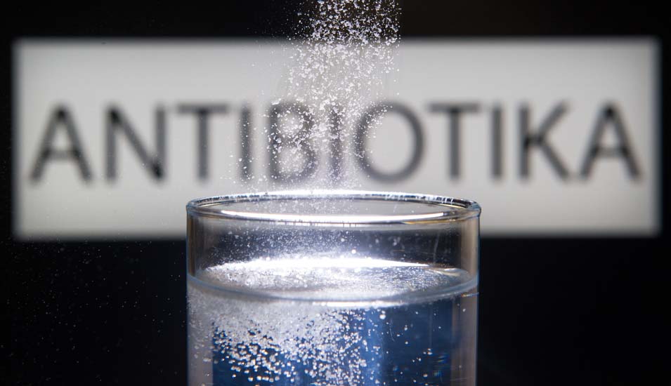 Das Bild zeigt ein Glas mit sprudelndem Wasser und dem Schriftzug Antibiotika
