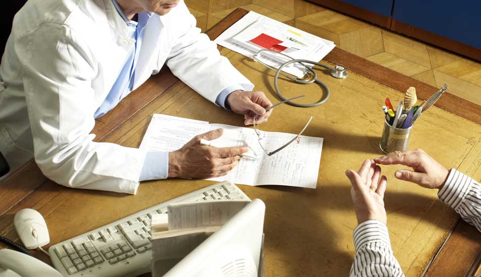 Das Foto zeigt eine Gesprächssituation an einem Schreibtisch zwischen Arzt und Patient.