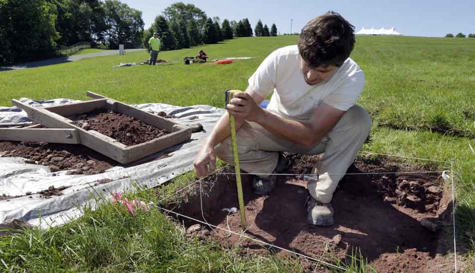 Das Foto zeigt einen Archäologen bei Ausgrabungen auf dem Gelände des Woodstock-Festivals.