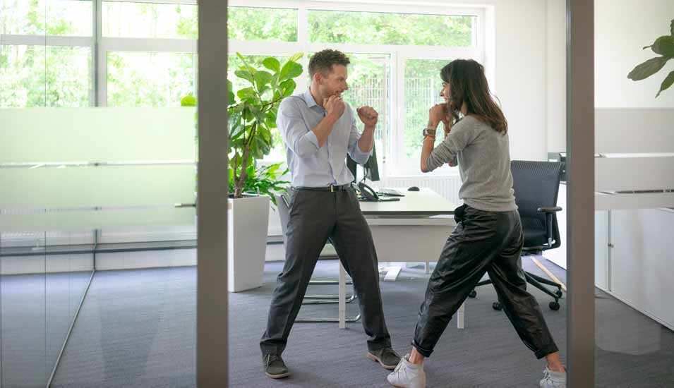 Frau und Mann boxen im Büro
