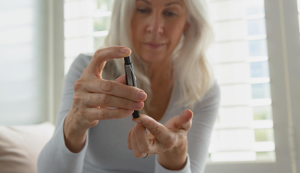 Ältere Frau testes ihren Blutzucker mit einem Diabetes-Testgerät