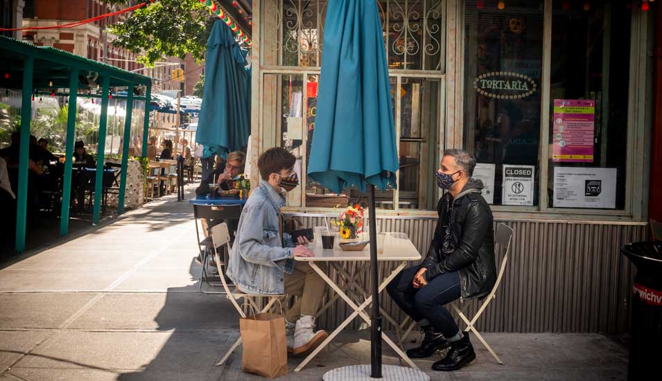 Personen mit Mundschutz im Außenbereich eines Restaurants in New York