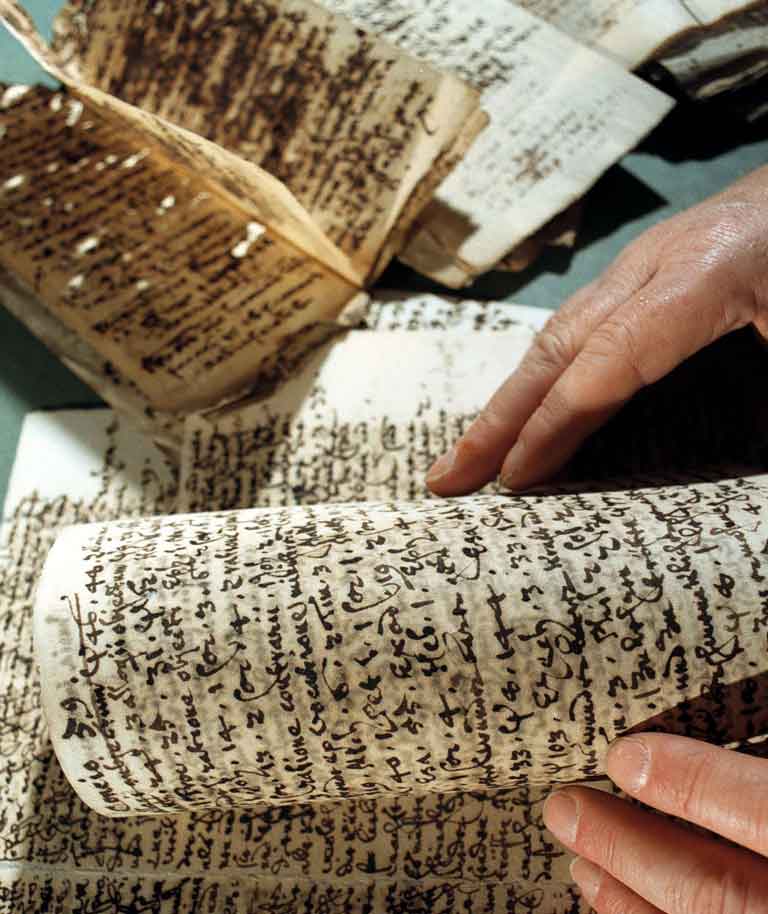 beschriebene historische Papierblätter, die durch Tintenfraß Löcher haben