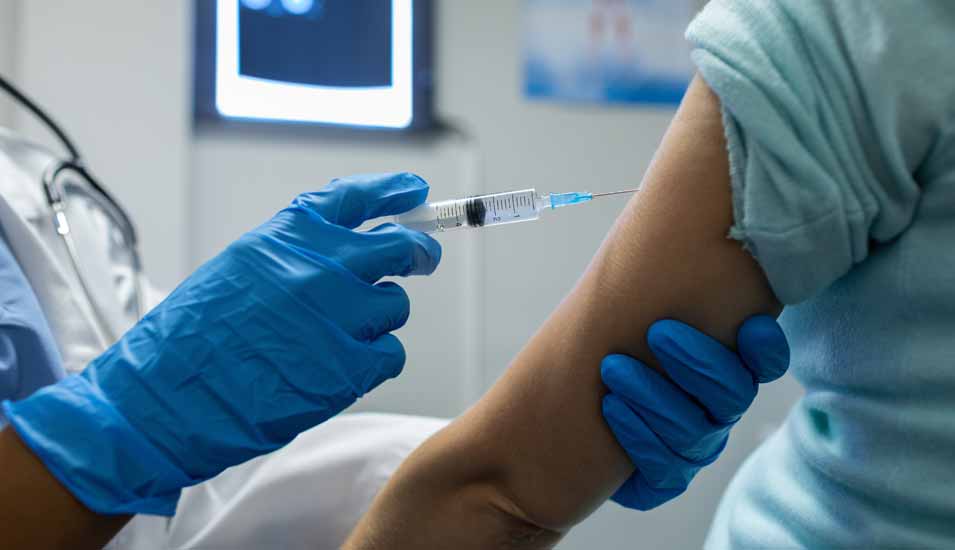 Ärztin spritzt einem Patienten einen Impfstoff in den Arm