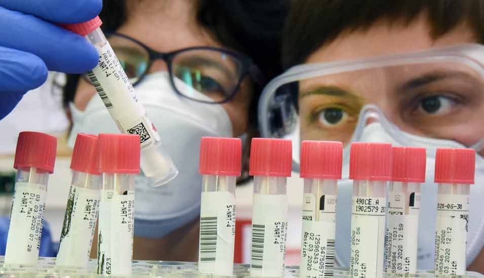 Zwei Laborassistentinnen betrachten in einem Labor Patientenproben, die auf das Coronavirus getestet werden