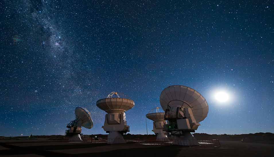Vier Antennen des Alma-Observatoriums der Europäischen Südsternwarte (Eso) in der Atacama-Wüste in Chile vor einem Sternenhimmel