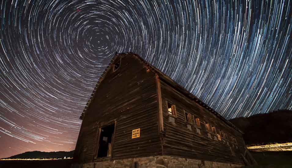 Langzeitaufnahme eines Sternenhimmels über einer Hütte