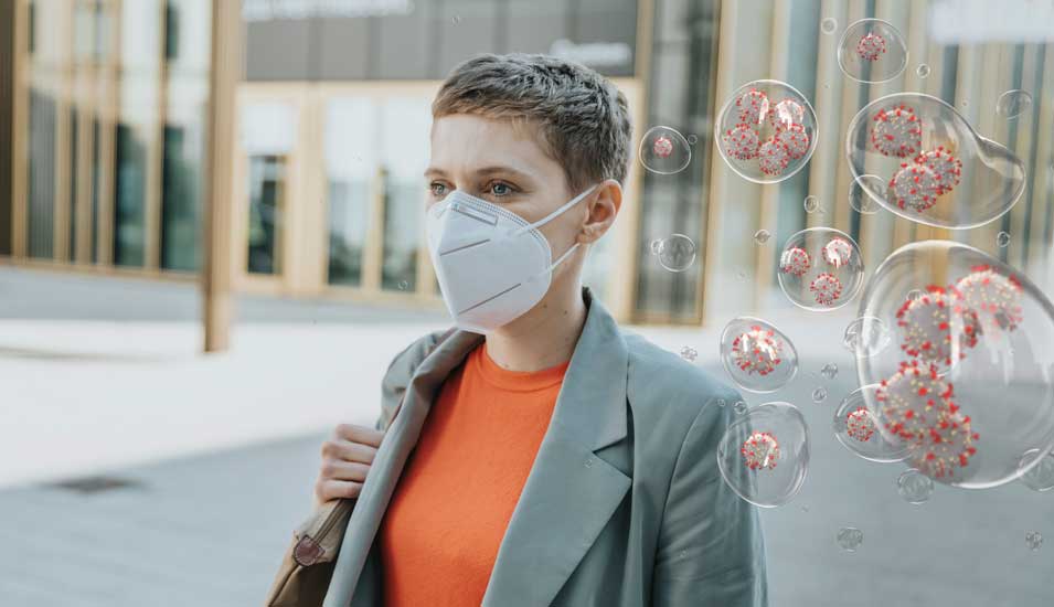 Frau mit FFP2-Maske, neben ihr gezeichnete Corona-Viren.