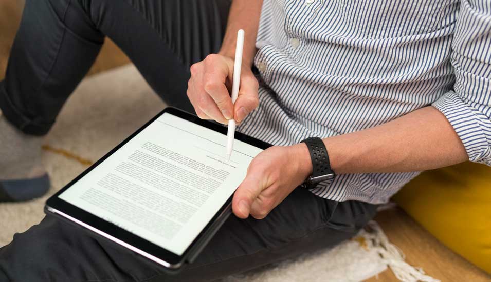 Ein digitaler Vertrag wird von einem Mann am Tablet unterschrieben.