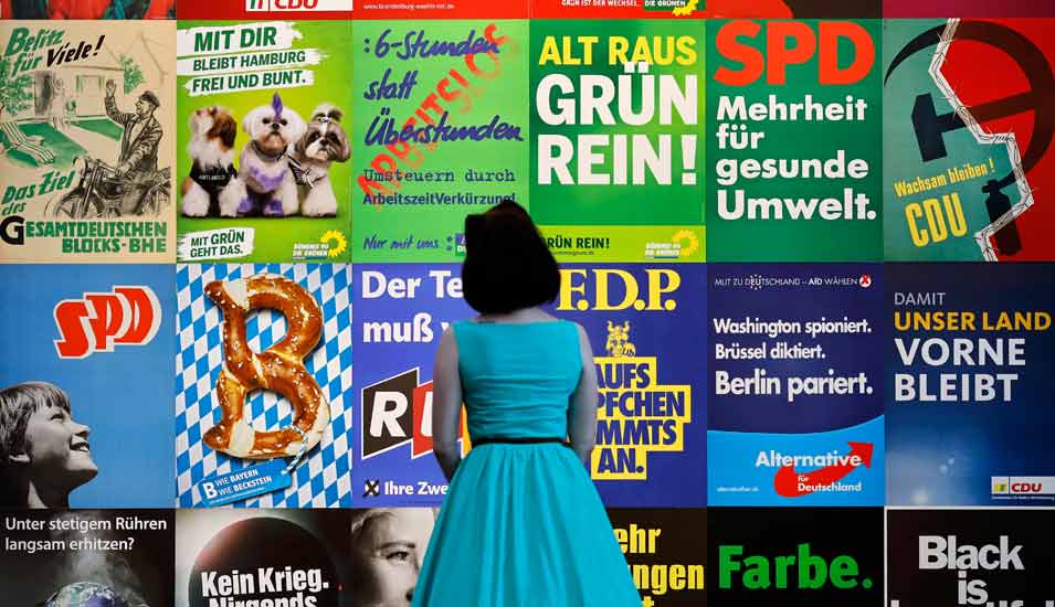 Frau betrachtet historische Wahlplakate aus Bundestags- und Landtagswahlen
