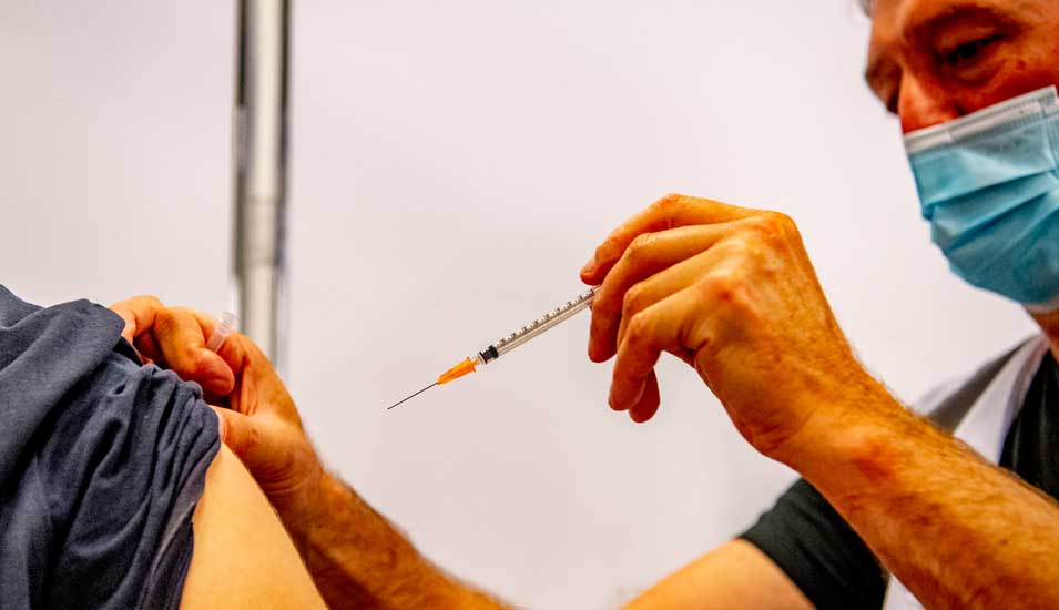 Ein Mediziner gibt einer Person eine Impfung.