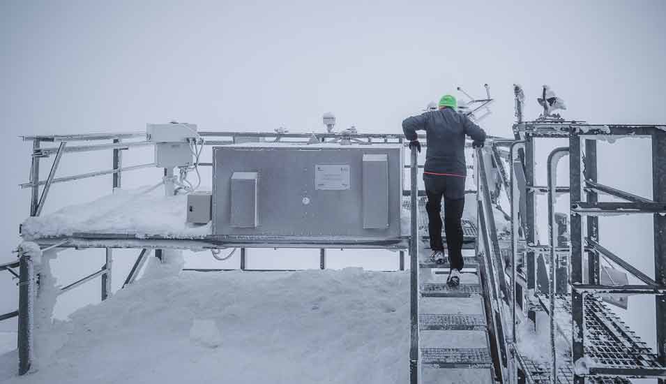 Ein Techniker des Sonnenblick-Observatoriums in den Hohen Tauern steigt auf eine verschneite Plattform mit Messgeräten.