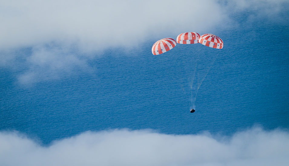 Die Orion-Kapsel wässert von Fallschirmen gebremst im Pazifik.