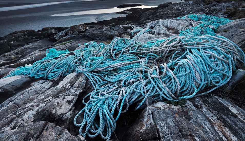 Plastiknetze und -seile aus der Fischerei, angespült an einer felsigen Küste