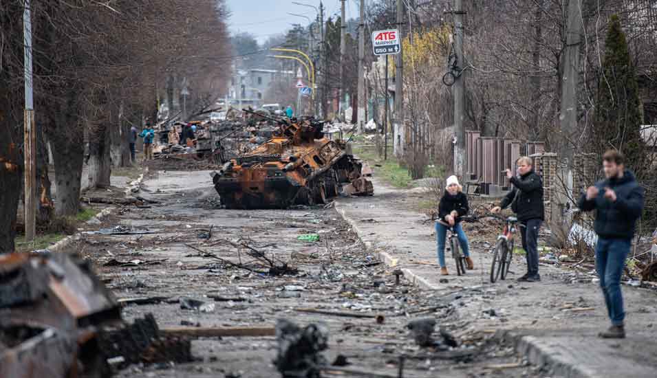Straßenansicht aus der ukrainischen Stadt Irpin: Zerstörte Panzer und Fahrzeuge, die von Menschen fotografiert werden.