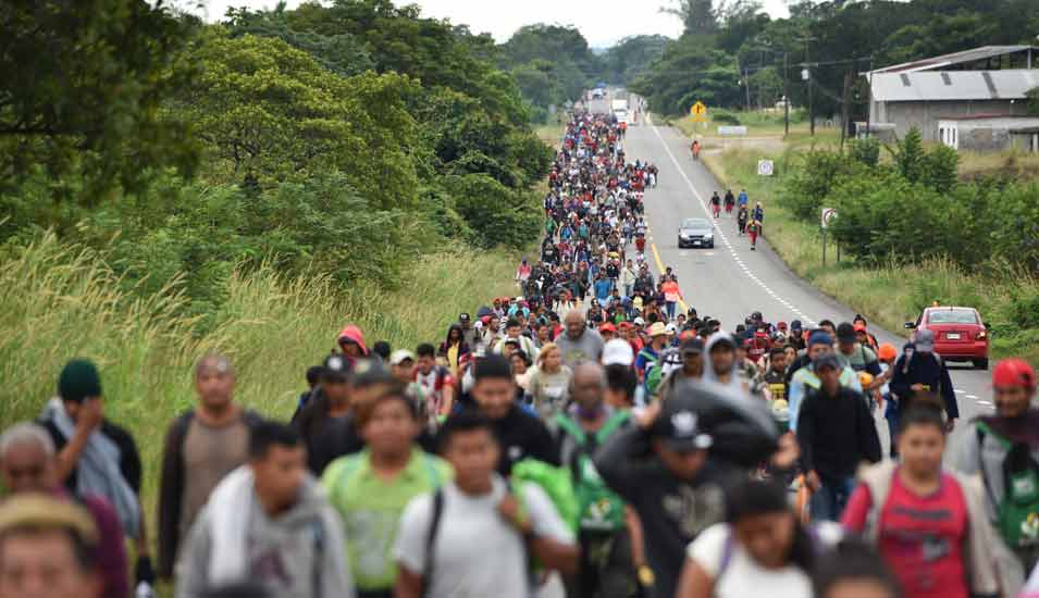 Zahlreiche Menschen aus Mittelamerika gehen gemeinsam zu Fuß an einer Landstraße in Richtung US-Grenze