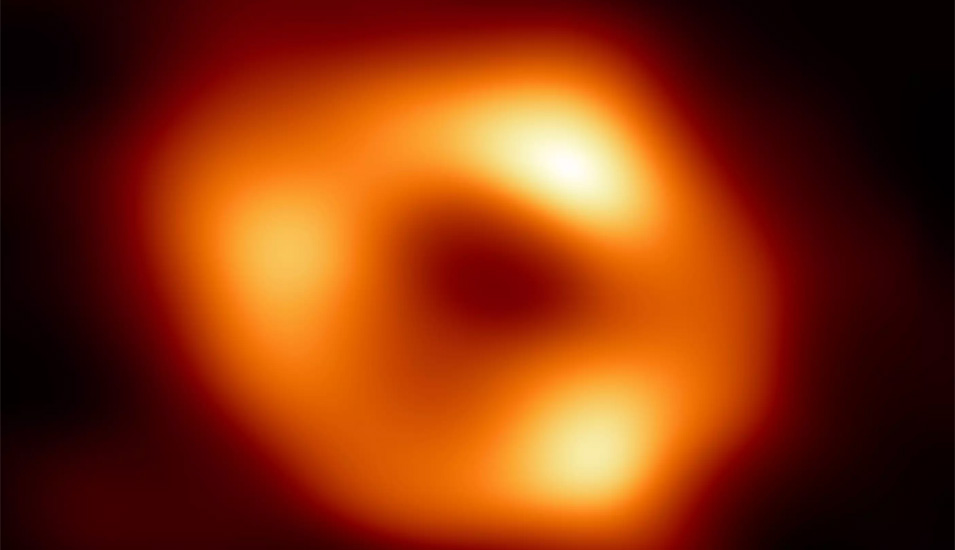 Ein dunkles Zentrum umringt von einem orangenem Leuchten, so erscheint das Schwarze Loch in der Mitte unserer Galaxie auf der ersten Abbildung. 