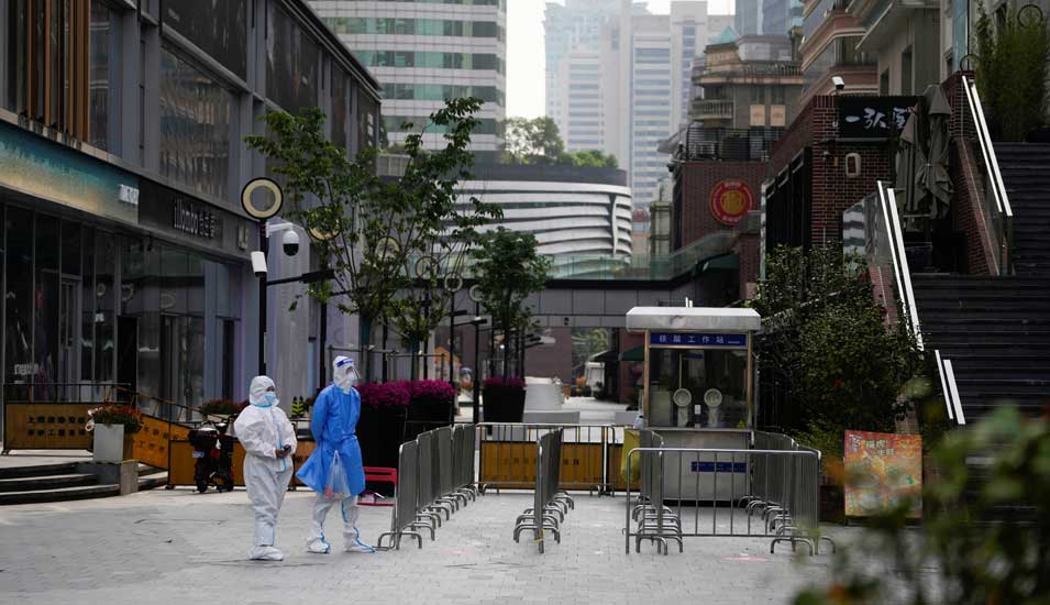 Menschen in Schutzkleidung auf einer Straße mit Absperrungen während des Lockdowns in Shanghai Anfang Mai 2022.
