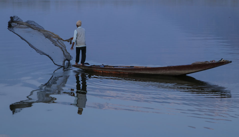 Ein Fischer in Indien wirft sein Netz aus