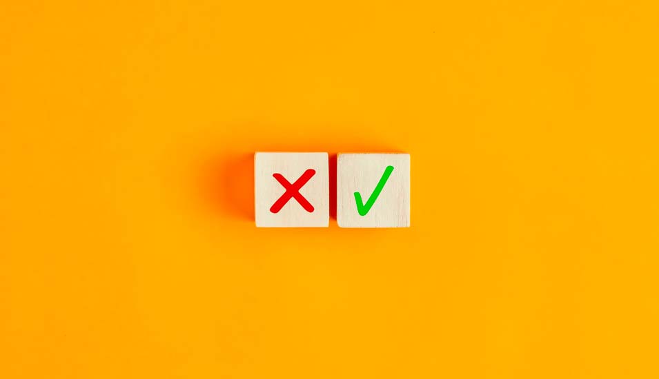 Symbolbild Zustimmung und Ablehnung: Zwei Holzwürfel mit Aufdruck von grünem Haken beziehungsweise rotem X
