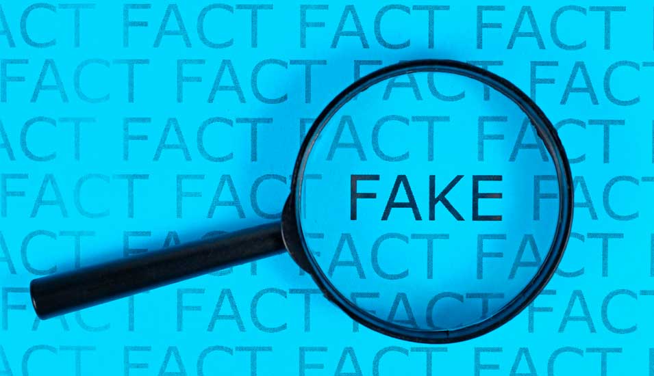 Auf der Suche nach gefälschten Artikeln: Eine Lupe vergrößert das Wort "Fake" zwischen vielen Wiederholungen des Wortes "Fact".