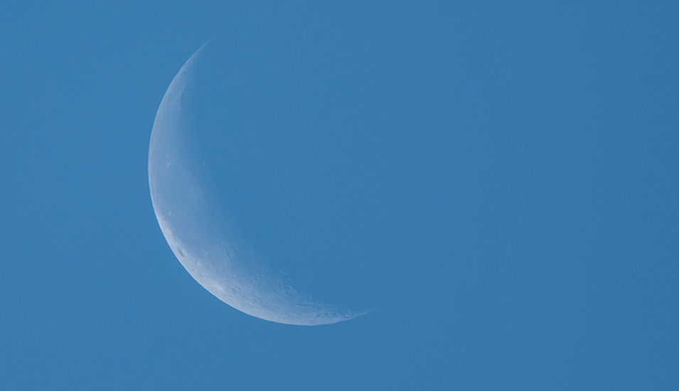Ein Foto der weißen Mondsichel in einem blauen Himmel