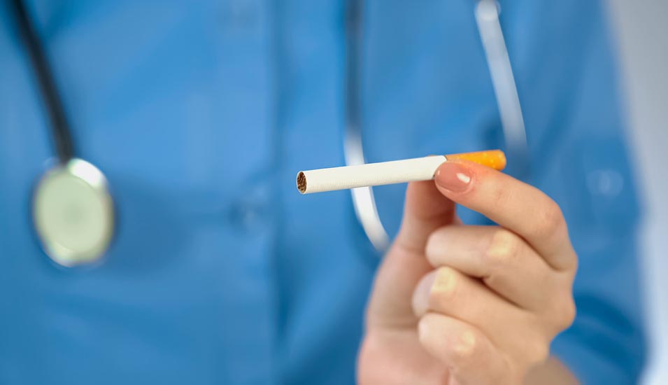 Eine Ärztin hält mahnend eine Zigarette mit spitzen Fingern