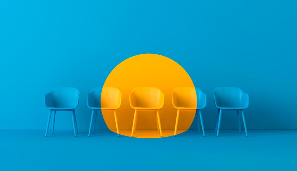 Gelber Stuhl zwischen mehreren blauen Stühlen