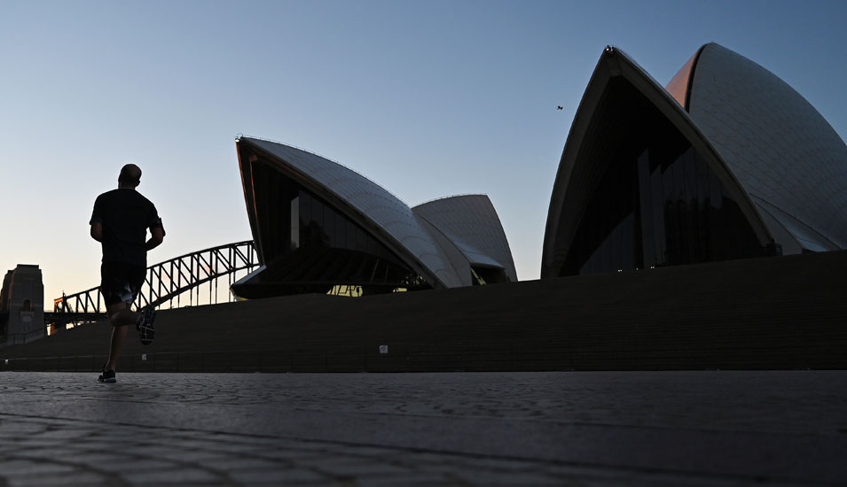 Eine Person joggt am Opernhaus von Sydney entlang.