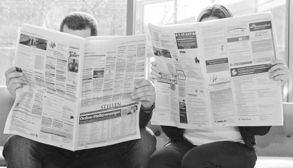Frau und Mann suchen nach Stellen in einer Zeitung