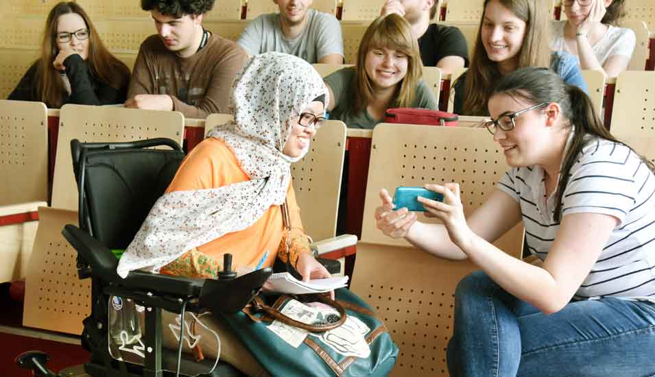 Das Foto zeigt eine behinderte Studentin mit Kommilitonen.