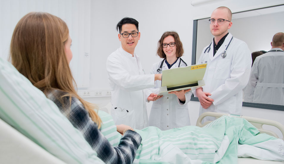 Drei Medizin-Studierende stehen am Bett einer Patientin