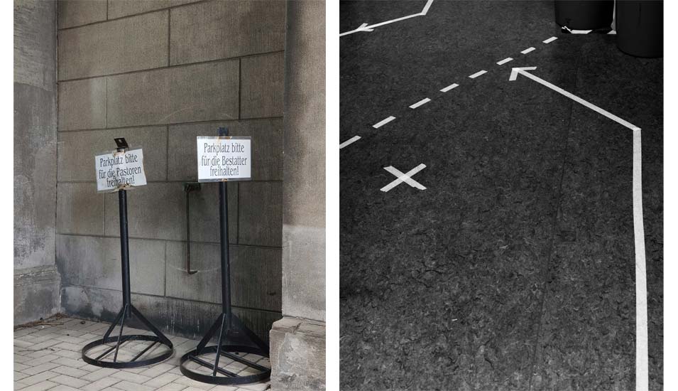Foto von weißen Wegmarkierungen auf Asphalt und Schildern mit der Aufschrift "Parkplatz für Pastoren" bzw. "Bestatter" 