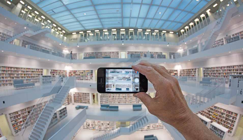 Mann mit Smartphone fotografiert Galeriesaal mit Treppenaufgängen der Stadtbibliothek Stuttgart
