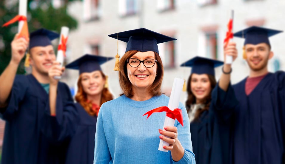 lächelnde ältere Studienabsolventin mit "Doktorhut" hält ihr Diplom in der Hand