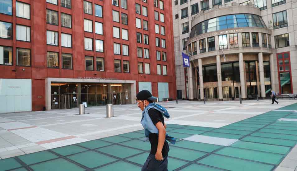 Das Foto zeigt einen jungen Mann, der über den Vorplatz der New York University geht.