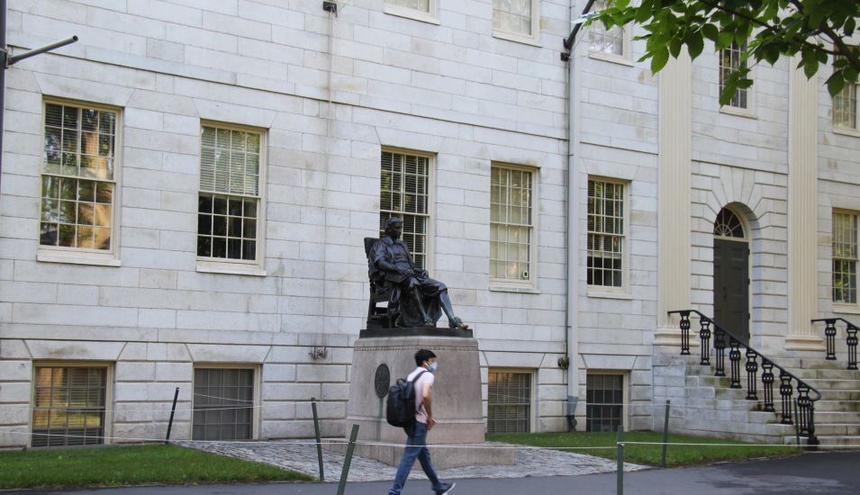 Das Foto zeigt einen Studenten vor einem Gebäude der Universität Harvard.