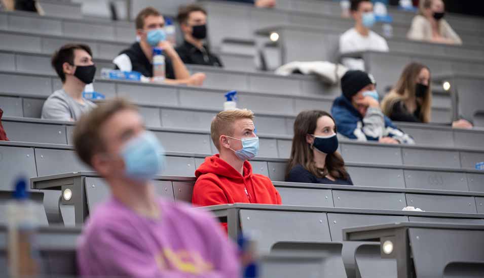 Studierende mit Mund- und Nasenmaske sitzen in der Begrüßungsveranstaltung für Studierende im ersten Semester an der Universität Hohenheim. 