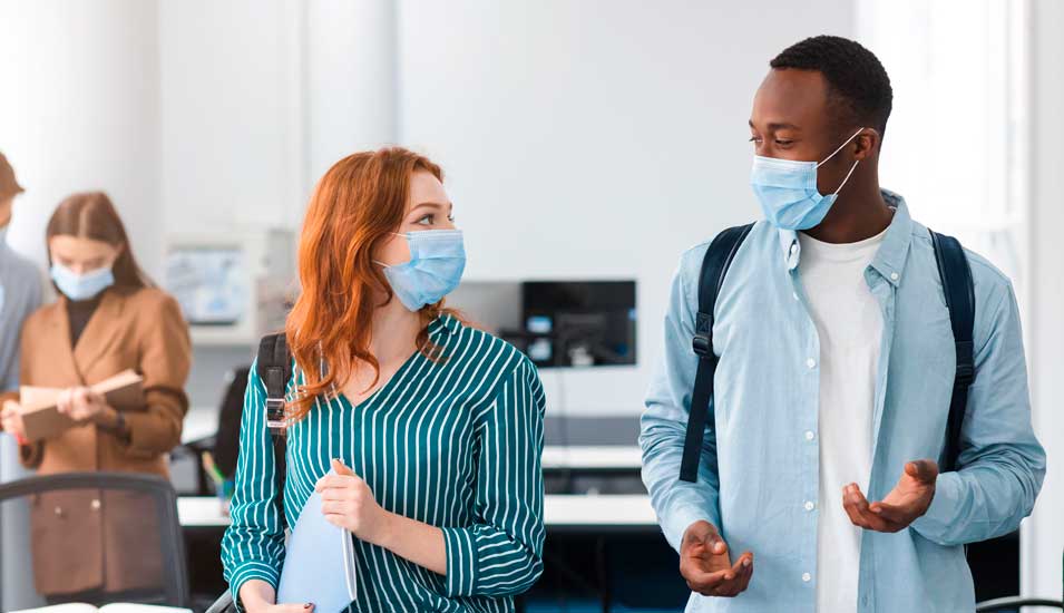 Internationale Studierende stehen zusammen und tragen medizinische OP-Masken.