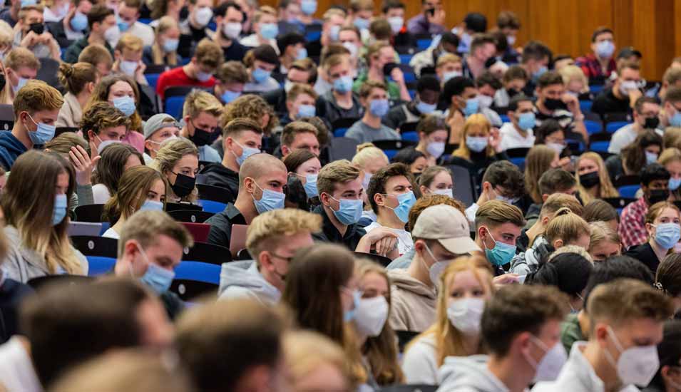 Studierende mit Mund-Nasen-Bedeckung sitzen dicht nebeneinander in einem Hörsaal der Universität Münster.