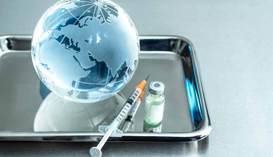 Tablett mit Gefäß für Impfstoff, einer Spritze und einem Globus