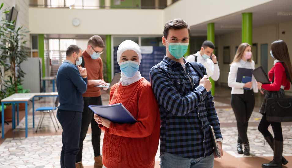 Kleine Gruppen von Studierenden mit Mundschutz in einem Universitätsgebäude